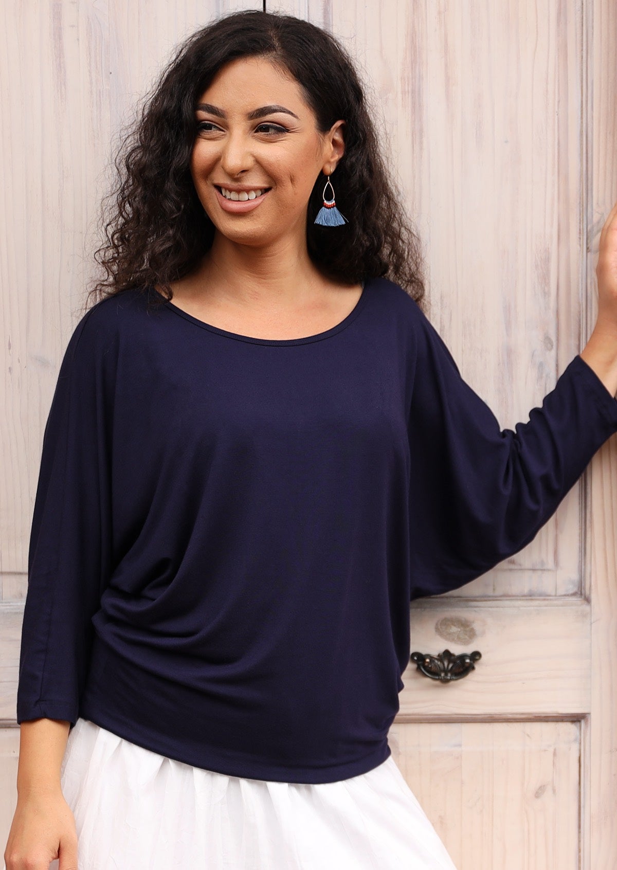 Woman wearing a 3/4 sleeve rayon batwing round neckline navy blue top with a white skirt.