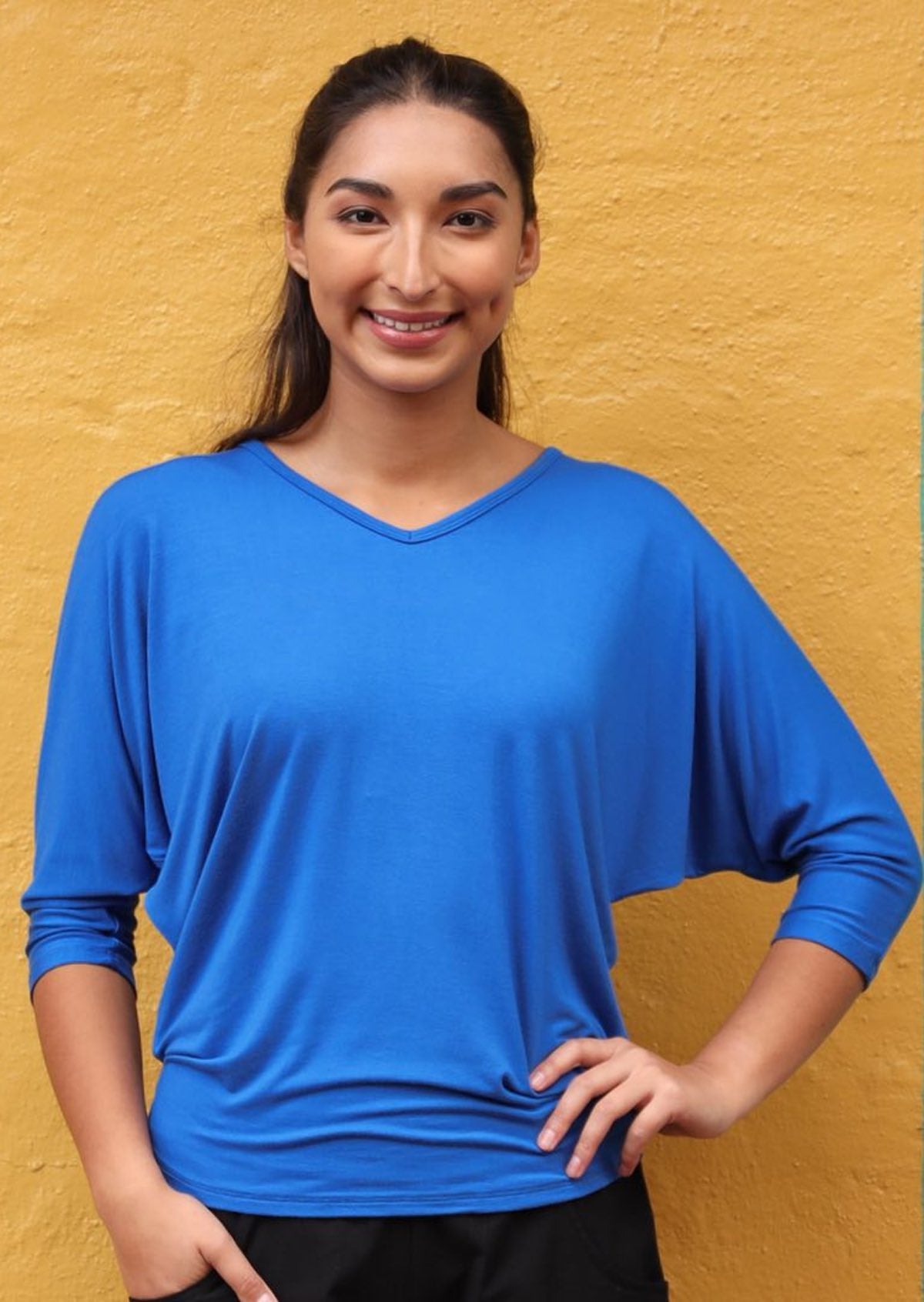 Woman wearing a 3/4 sleeve rayon batwing v-neck blue top.