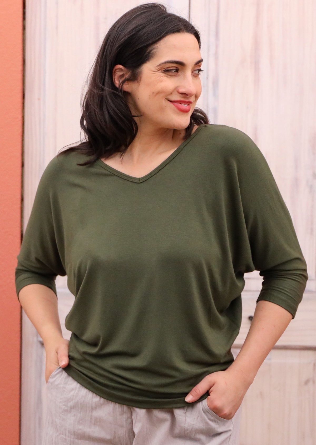 Woman wearing a 3/4 sleeve rayon batwing v-neck olive top.