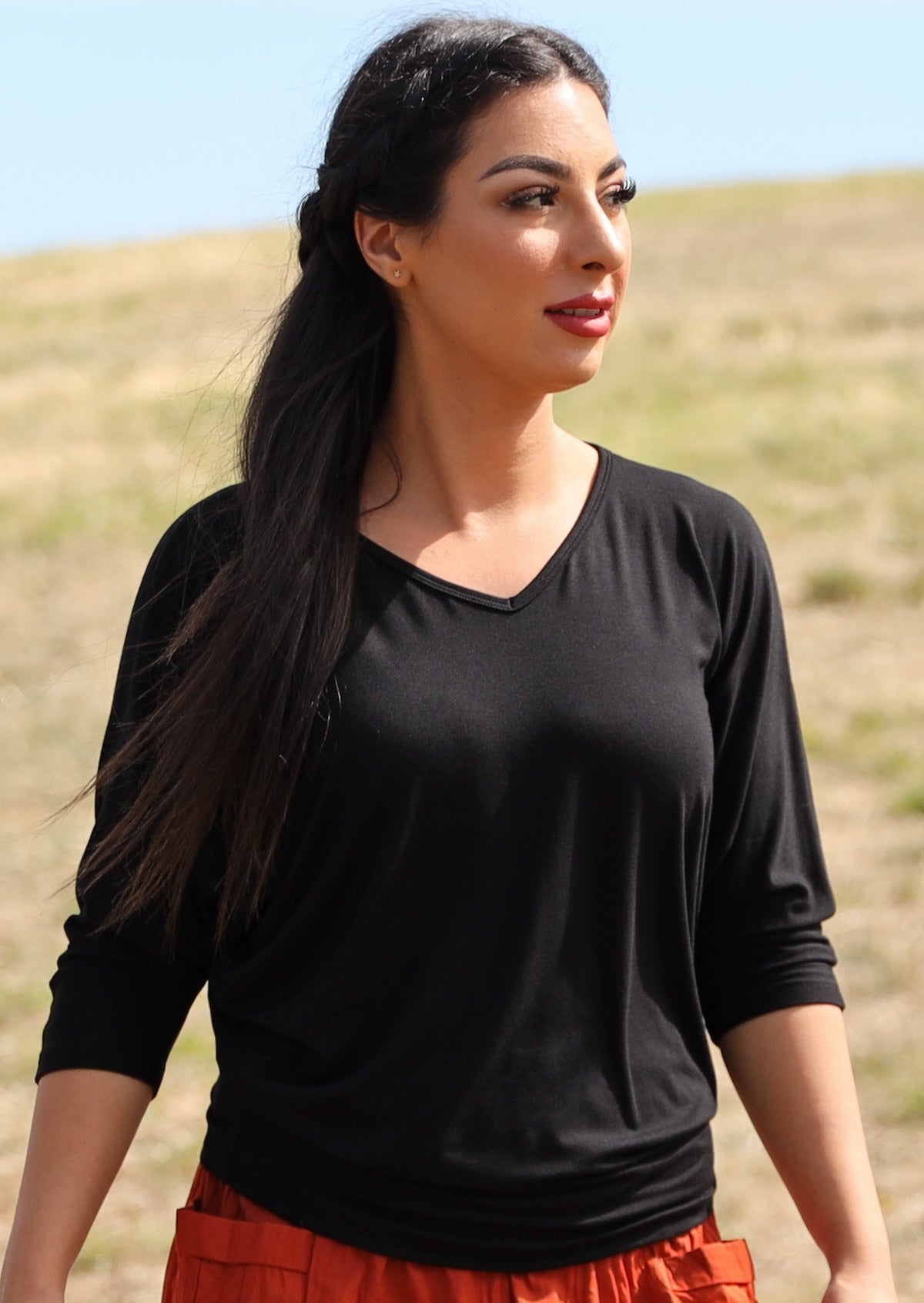 Woman wearing a 3/4 sleeve rayon batwing v-neck black top.