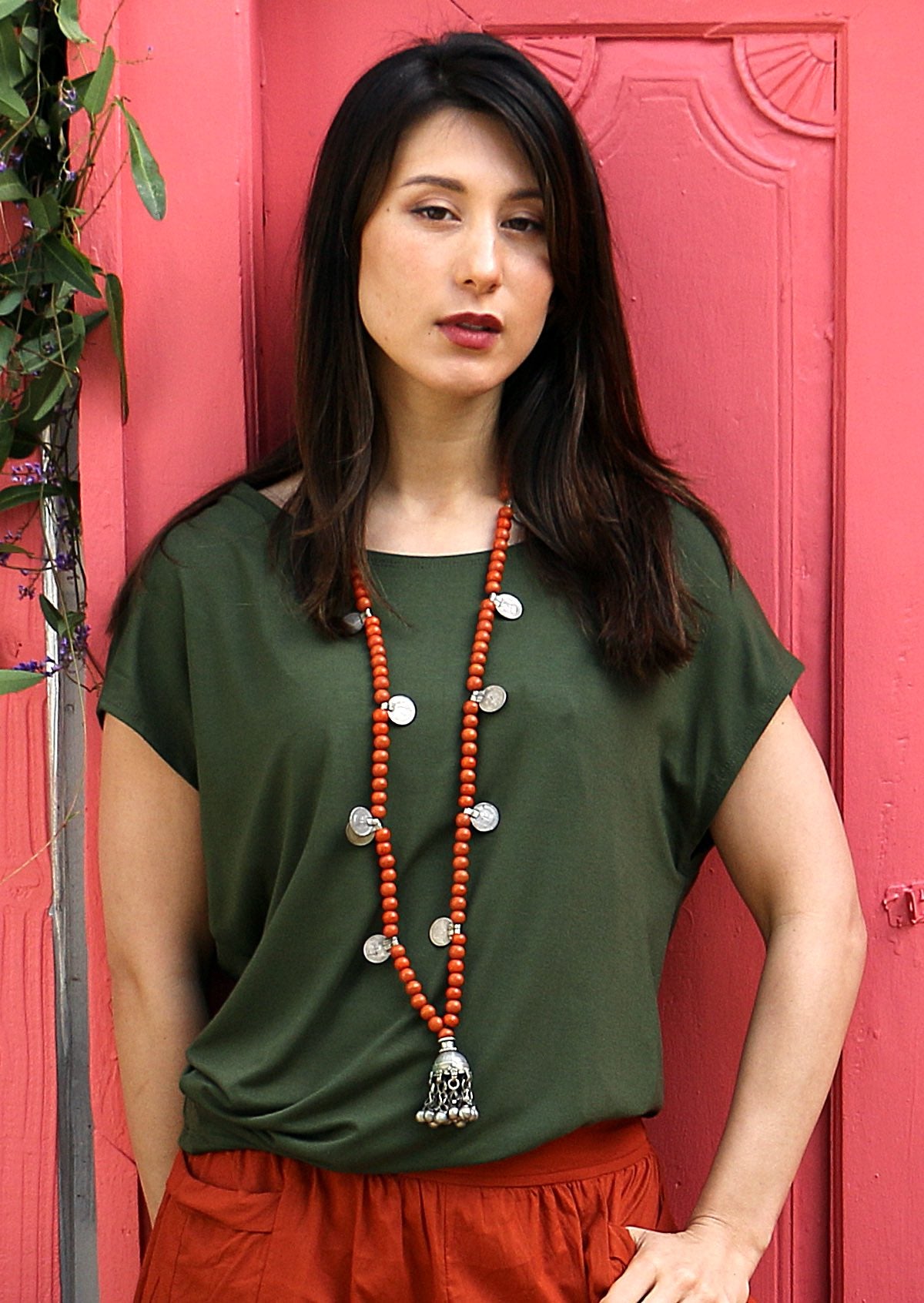 Woman wearing olive green rayon top with orange pants and necklace
