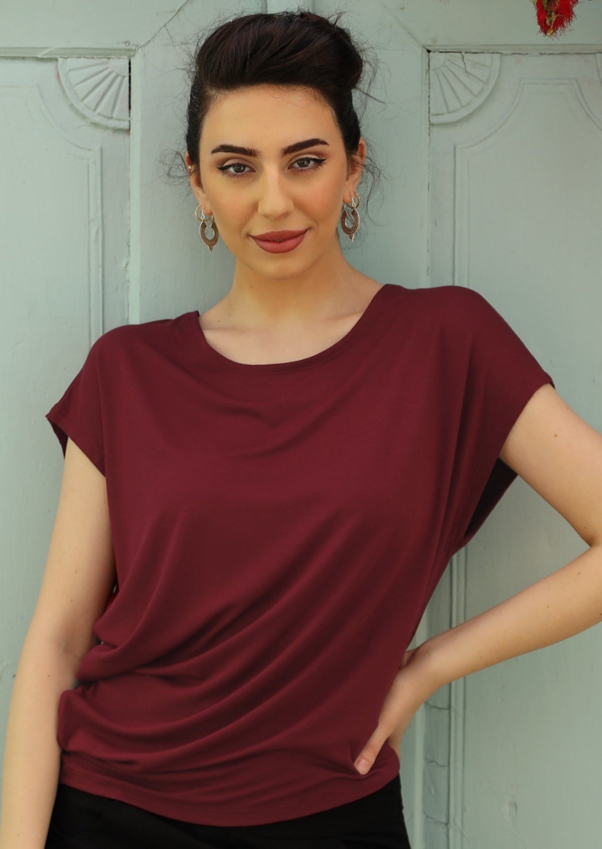 Woman wearing asymmetrical rayon maroon top with round neckline