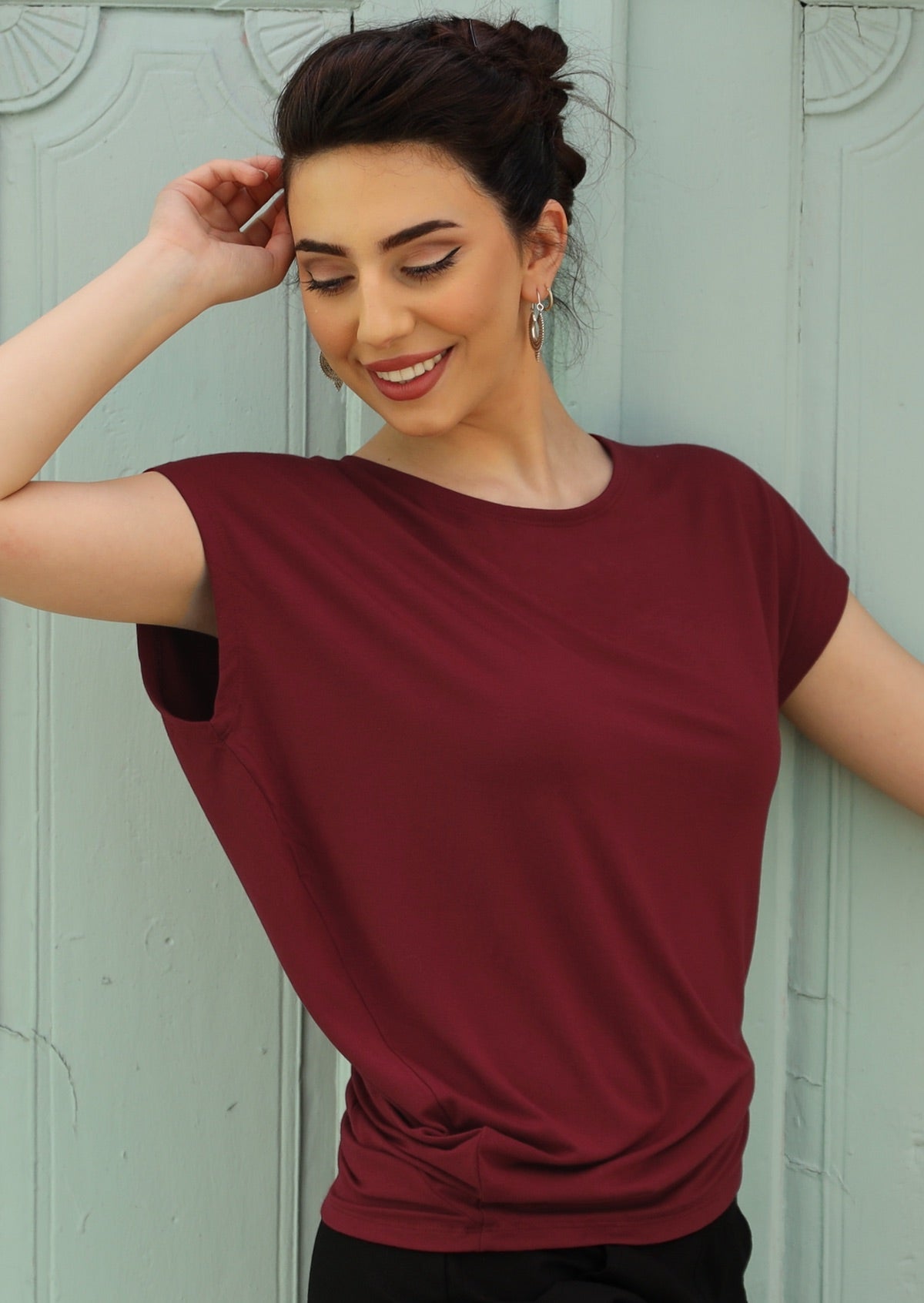 Woman wearing short sleeve maroon basic top with asymmetrical detail
