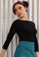 Woman with dark hair in two buns wearing a rayon boat neck black 3/4 sleeve top