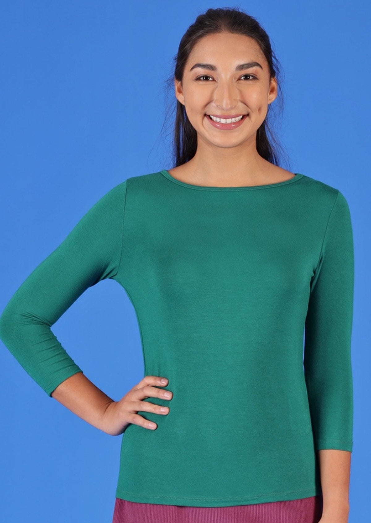 Woman wearing a rayon boat neck green 3/4 sleeve top.