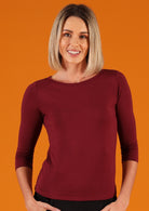 Woman wearing a rayon boat neck maroon 3/4 sleeve top.