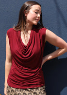 Woman wearing a cowl neck rayon maroon cap sleeve top.