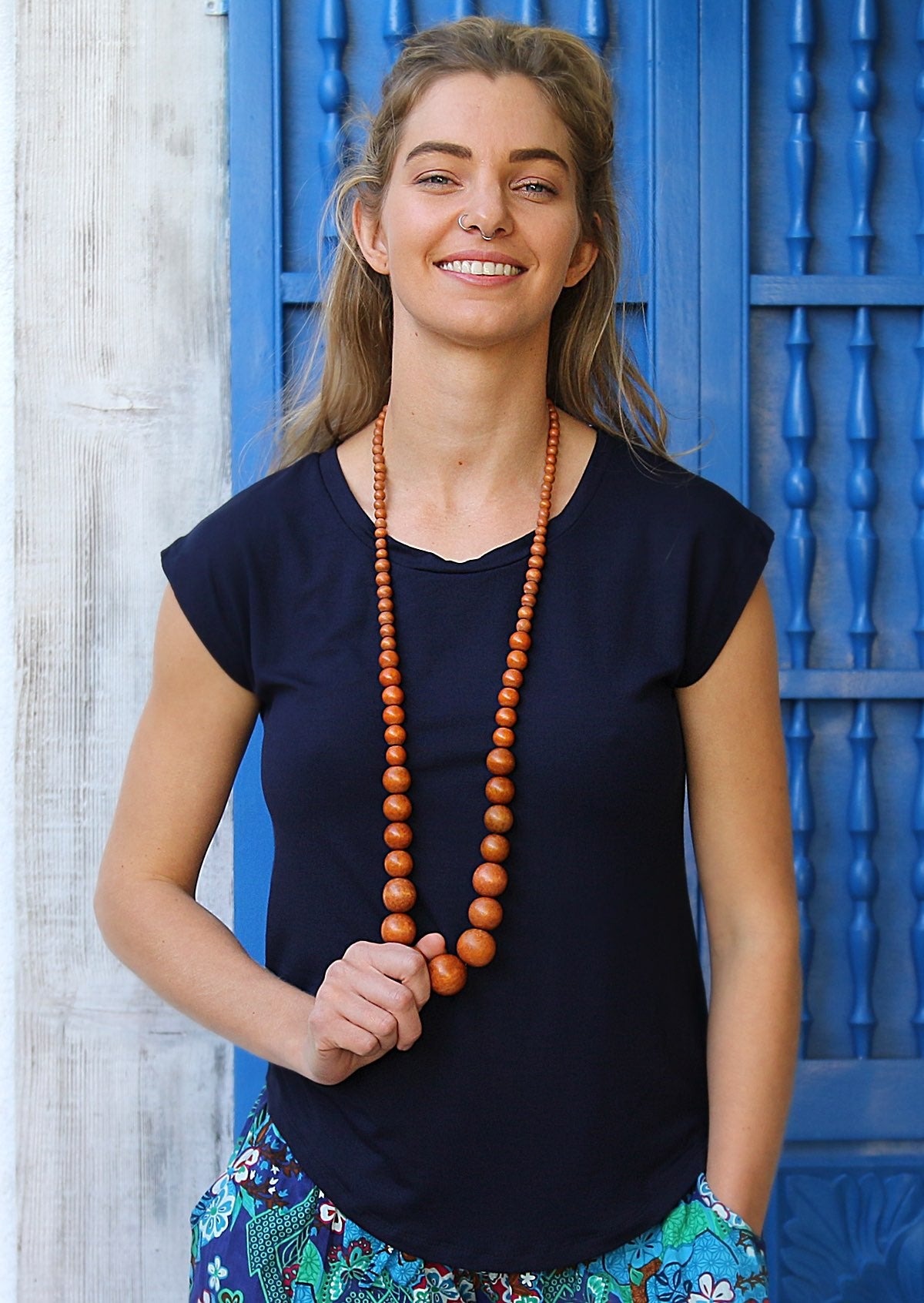 Woman wearing a soft flattering fit navy blue rayon jersey t-shirt with wooden beads.