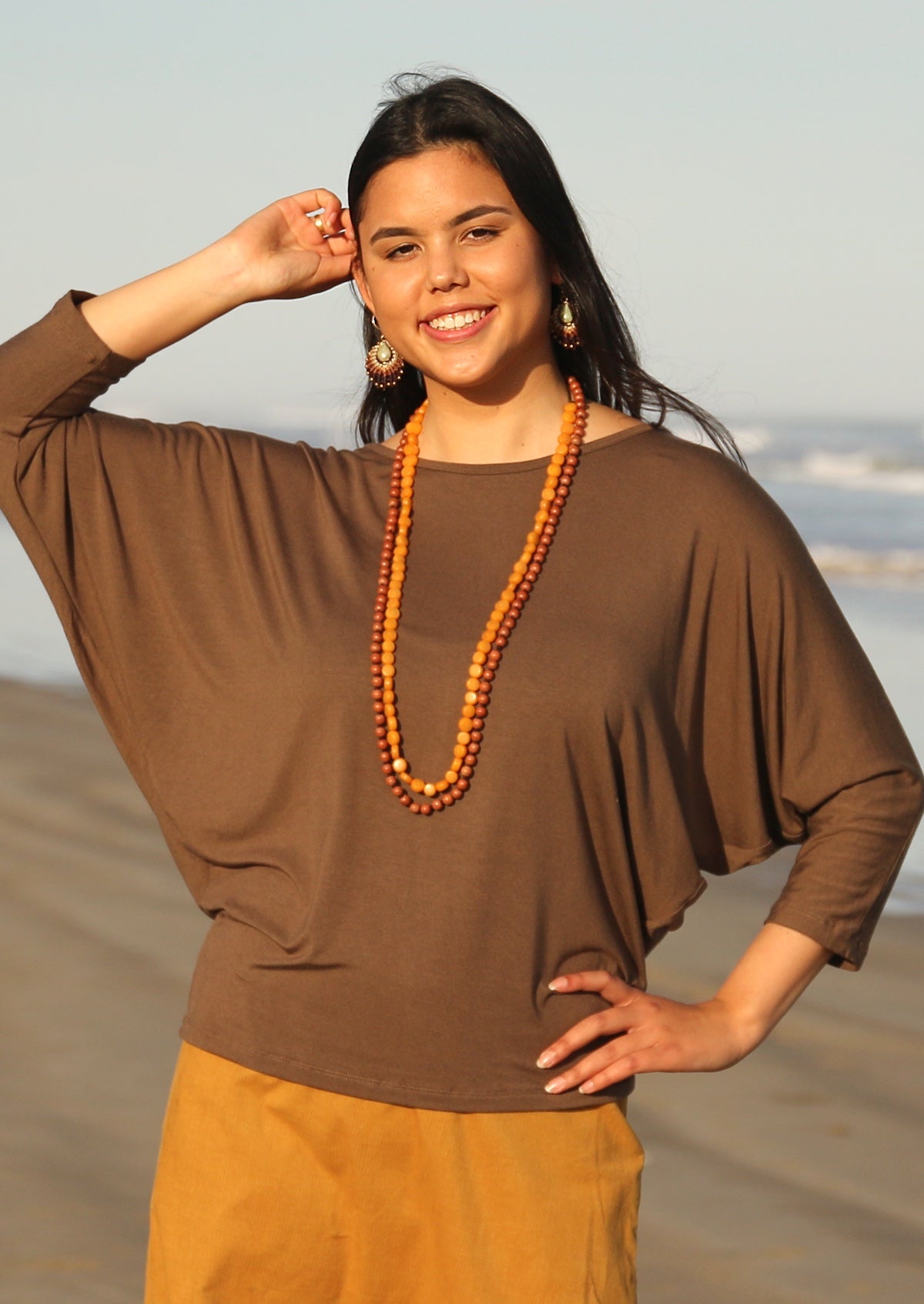 Woman wearing a 3/4 sleeve rayon batwing round neckline brown top.