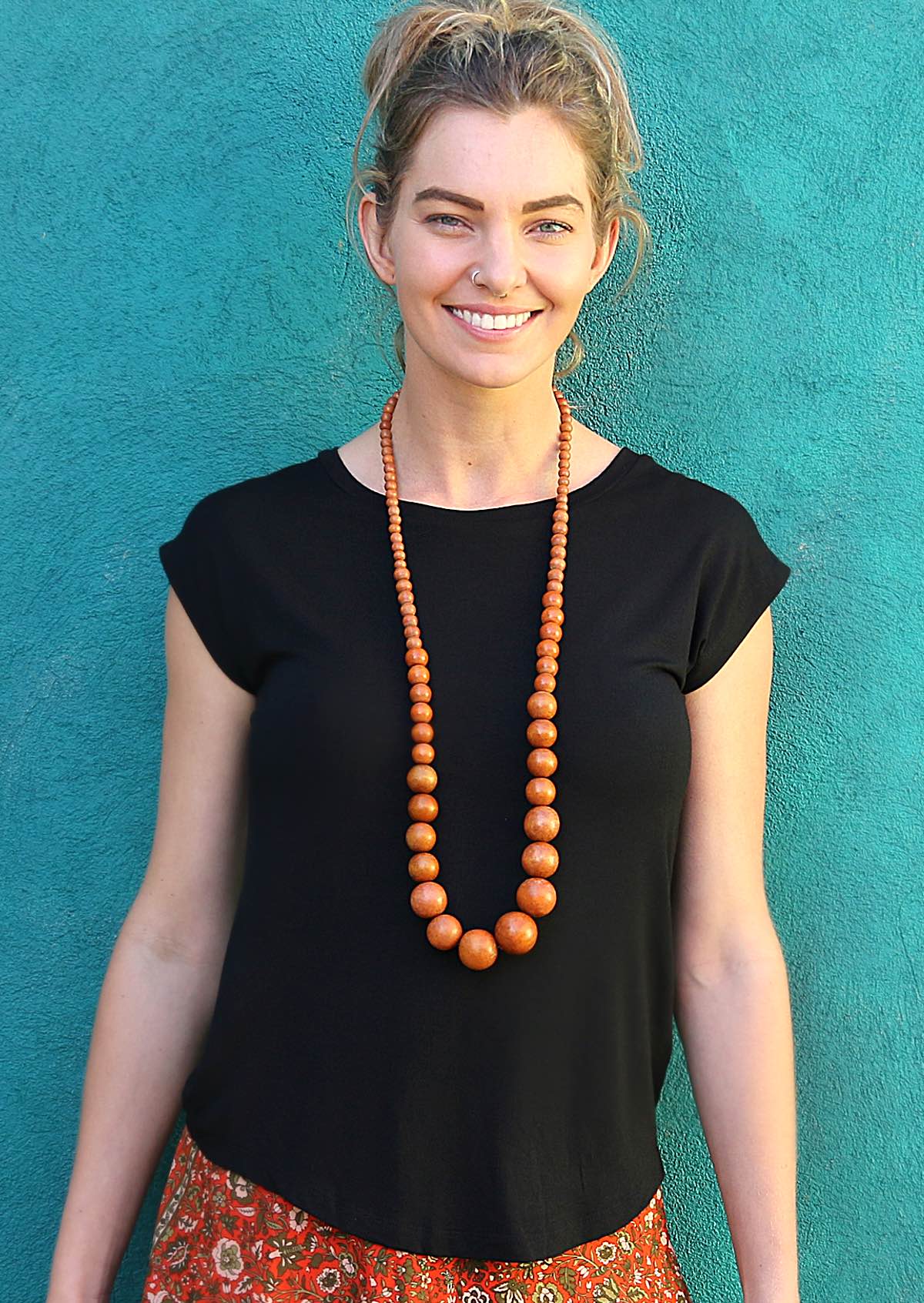 Woman wearing a soft flattering fit black rayon jersey t-shirt with wooden beads.