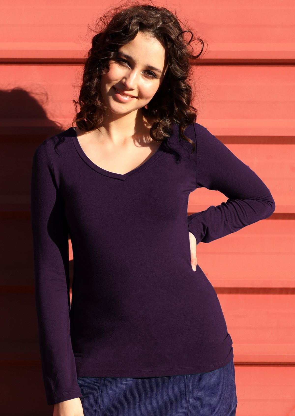 Woman with dark hair wearing purple long sleeve stretch v-neck soft rayon top.