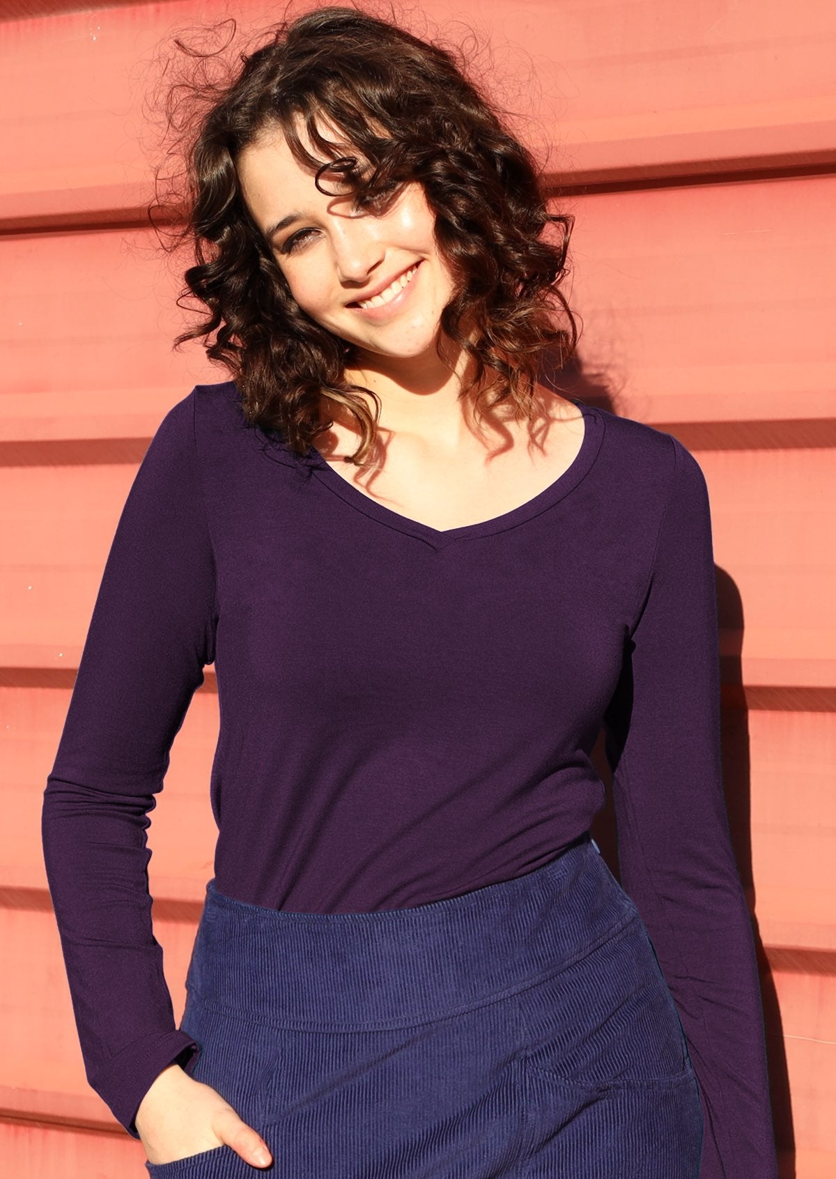 Woman wearing purple long sleeve stretch v-neck soft rayon top.