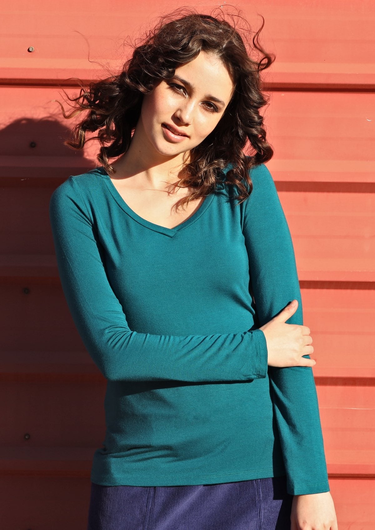 Woman wearing a teal long sleeve stretch v-neck soft rayon top.
