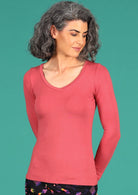 Woman wearing a rose pink long sleeve stretch v-neck soft rayon top.