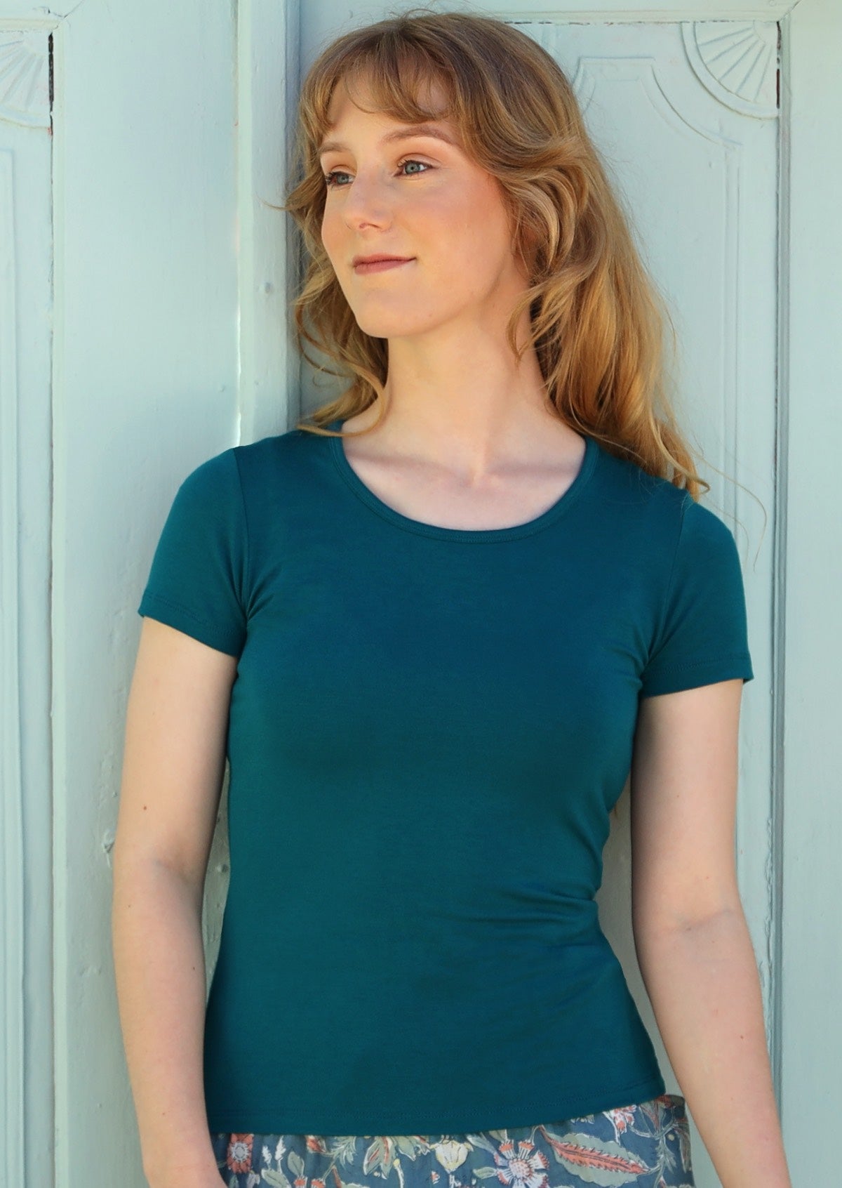 Woman wearing a scoop neck teal rayon fitted t-shirt.