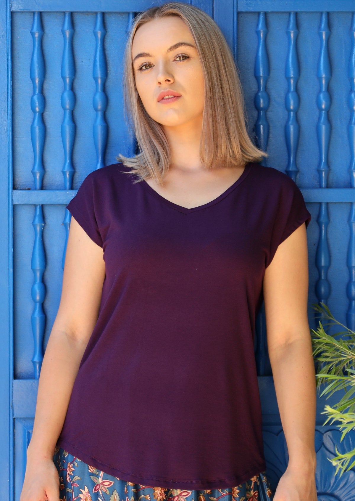 Woman wearing a dark purple v-neck short cap sleeve rayon top