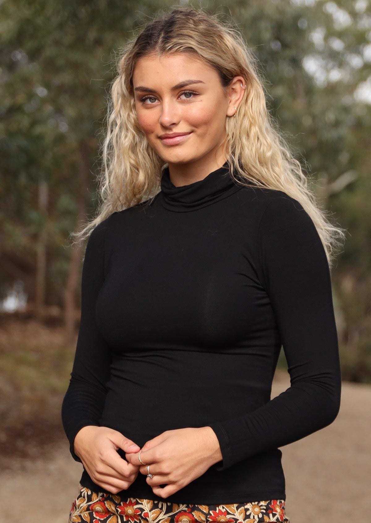 Woman wearing a turtle neck black fitted long sleeve soft stretch rayon top.
