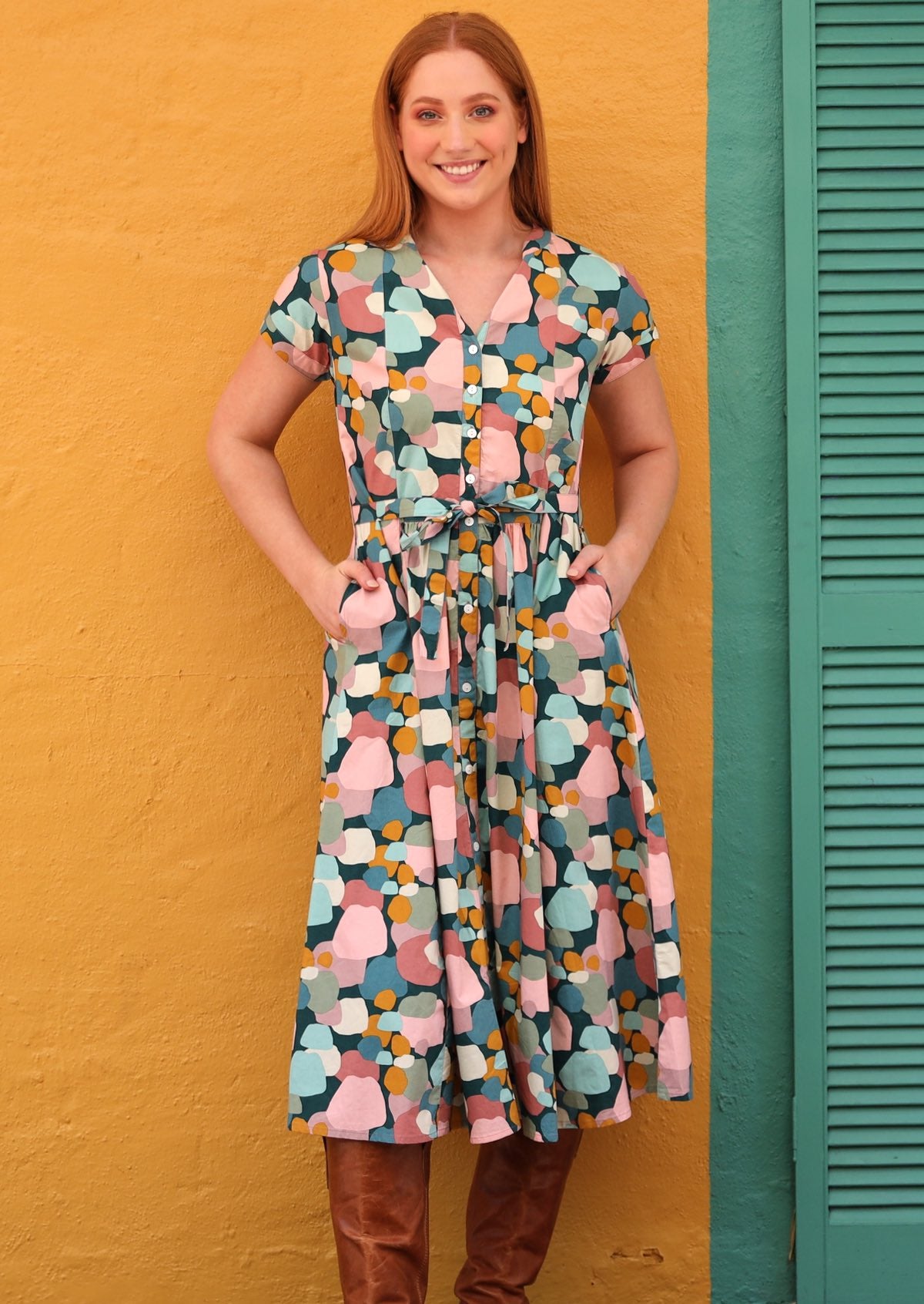 Model wears 100% cotton button through dress with detachable waist tie and hands in pocket.