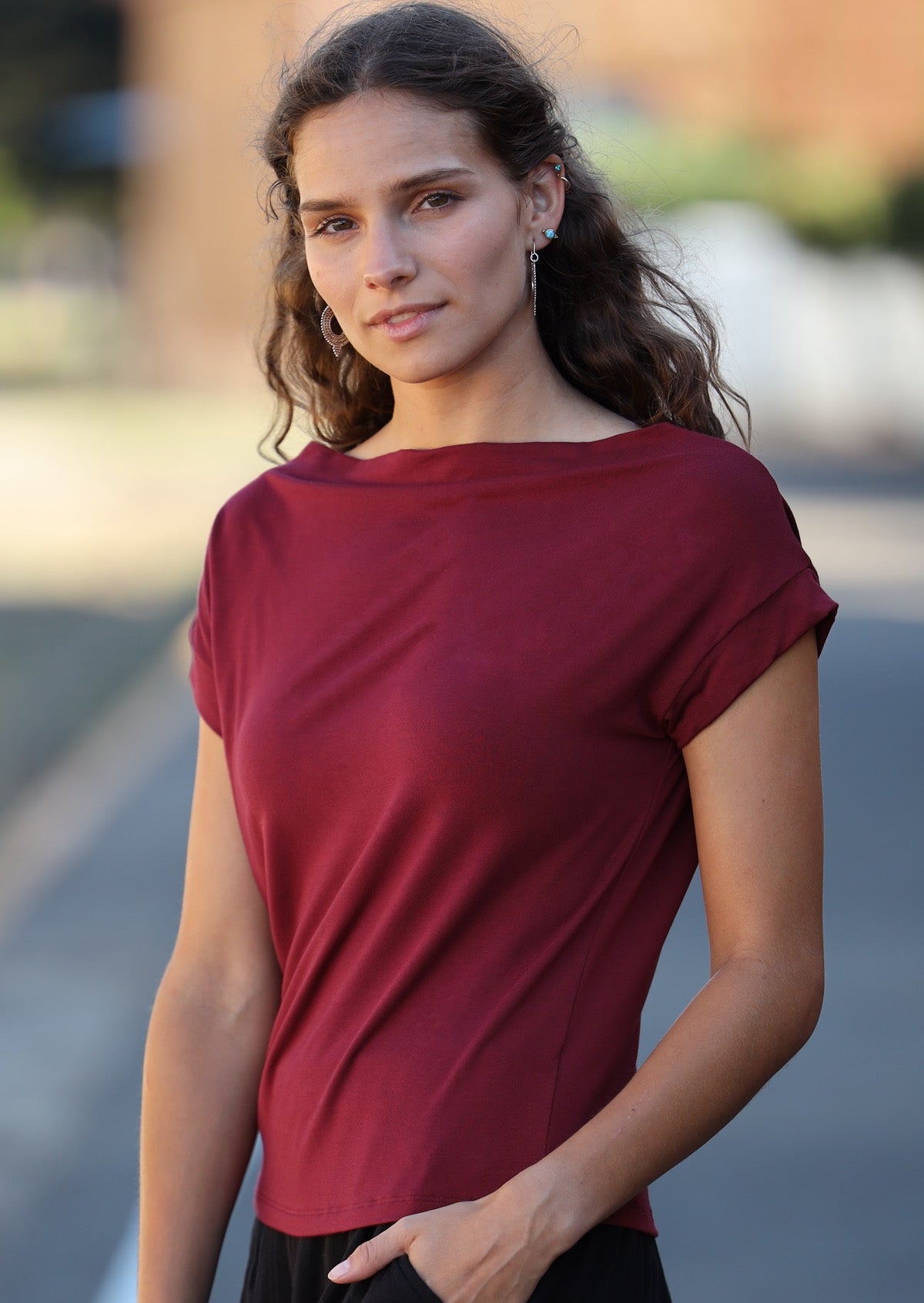 Woman with brown hair wearing a wide neck mod maroon stretch rayon boat neck top