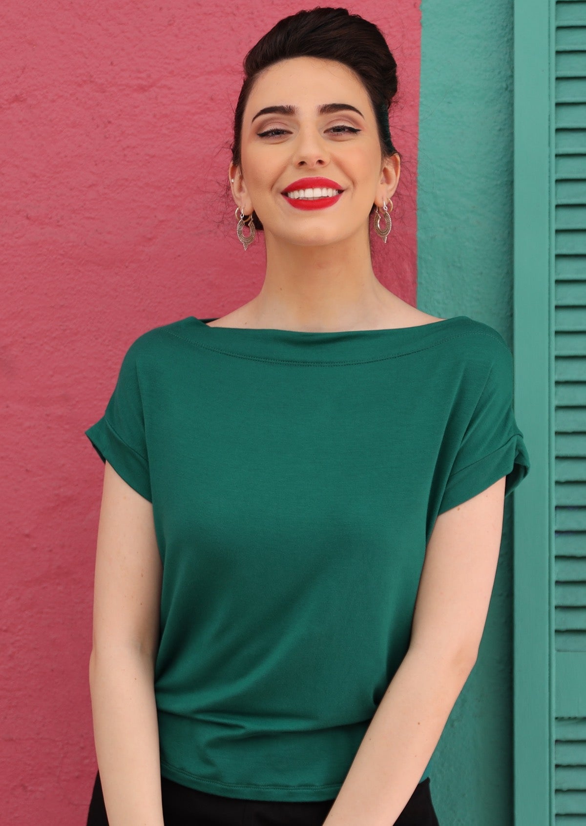 Woman with dark hair wearing a wide neck mod green stretch rayon boat neck top