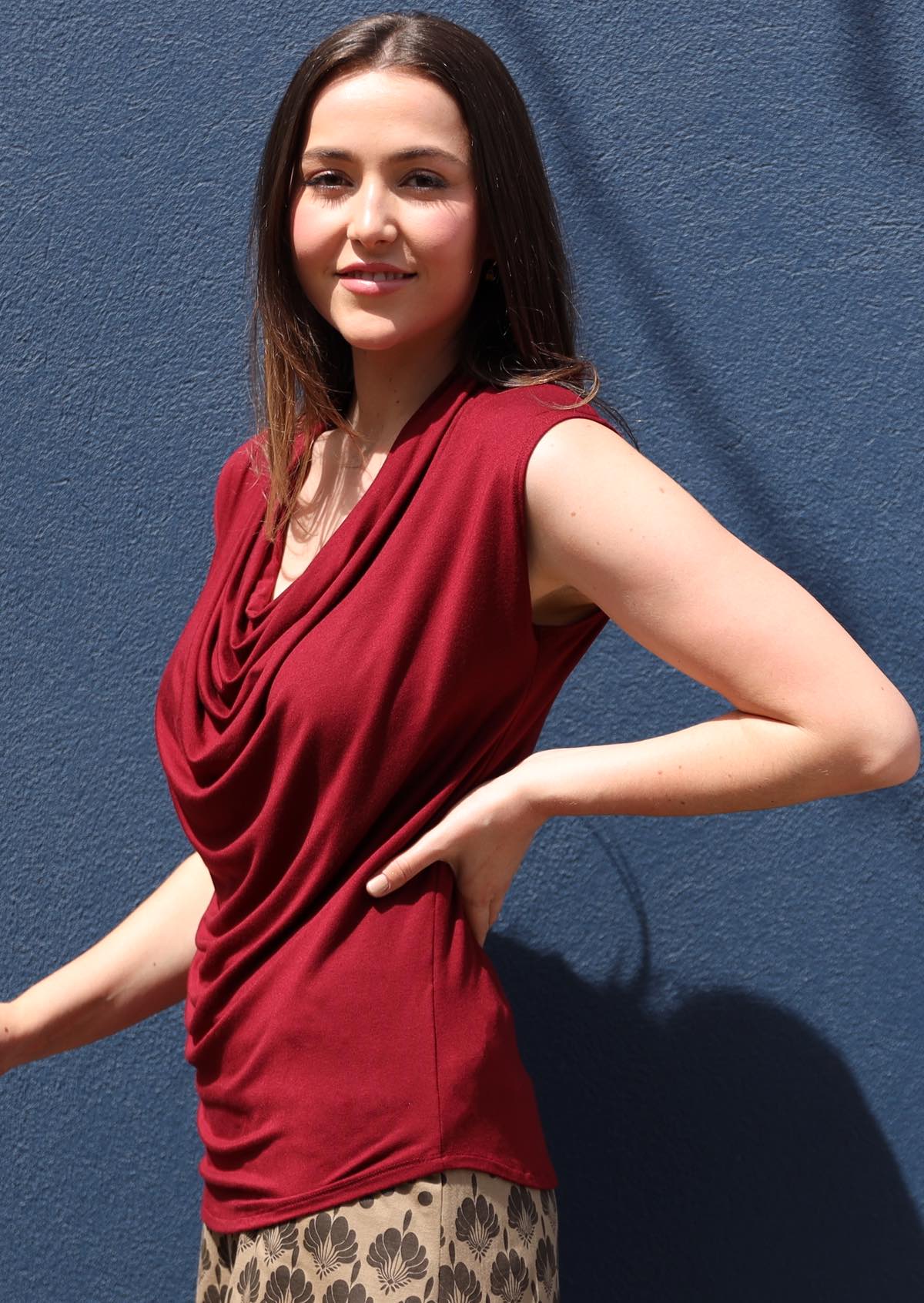 Side view of woman wearing a cowl neck rayon maroon cap sleeve top.