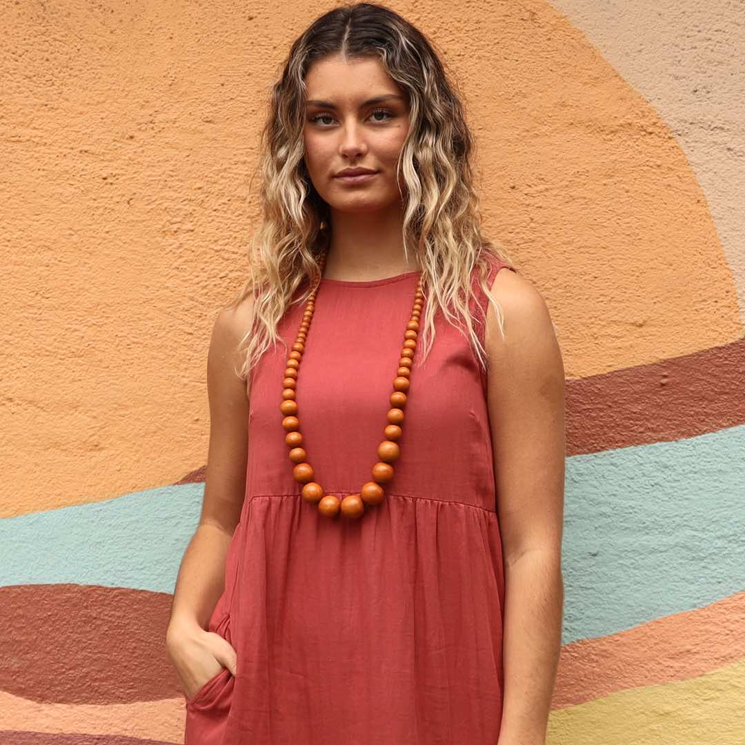 woman wearing pink dress and tan wooden bead necklace