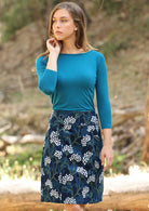 Woman wears corduroy above knee skirt with gorgeous floral print, paired with a 3/4 sleeve teal top