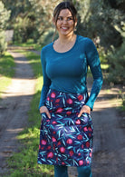 Woman wears blue based skirt with pockets.