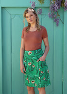 Model wears green floral print cotton skirt with accent piping details