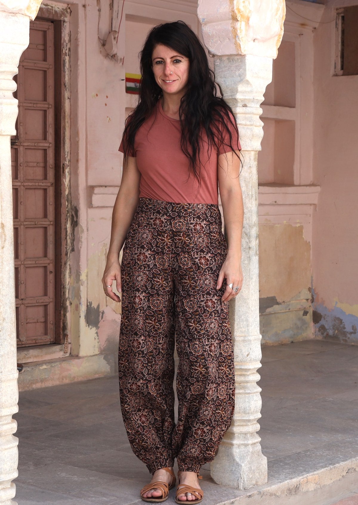 Model in dark brown cotton harem pants with buttoned ankle, pockets, and a stretch rayon top in dusty rose