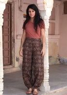 Model in dark brown cotton harem pants with buttoned ankle, pockets, and a stretch rayon top in dusty rose