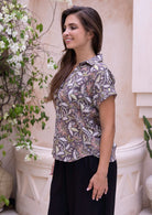 Woman wearing a 100 percent cotton floral shirt top in light brown, paired with black pants 