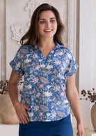 Woman poses in relaxed fit cotton short sleeve top with rolled cuffs sleeves, collar and V neckline.