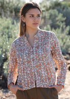 Model wears 100% cotton top with a cream, green and peach floral print. This long sleeve top features a mandarin-style collar and a button-down front. 
