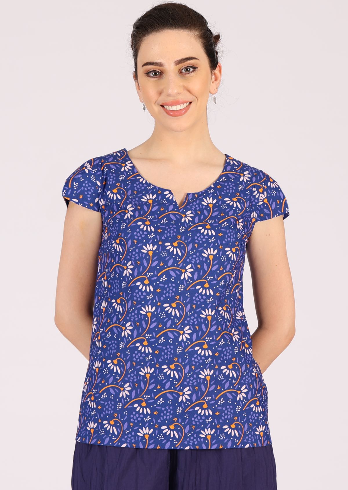 Model wears 100% cotton top in blue with short sleeves that falls below the hip.