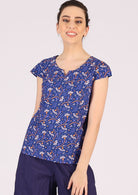 Model styles 100% cotton top with playful florals on a blue base with dark blue pants. 