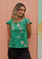 Woman wears floral top with a green base. 