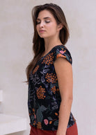Woman wearing a 100% cotton black tailored top with cap sleeves and round neckline.