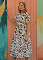 Model wears floral cotton midi length dress cinched with leather belt