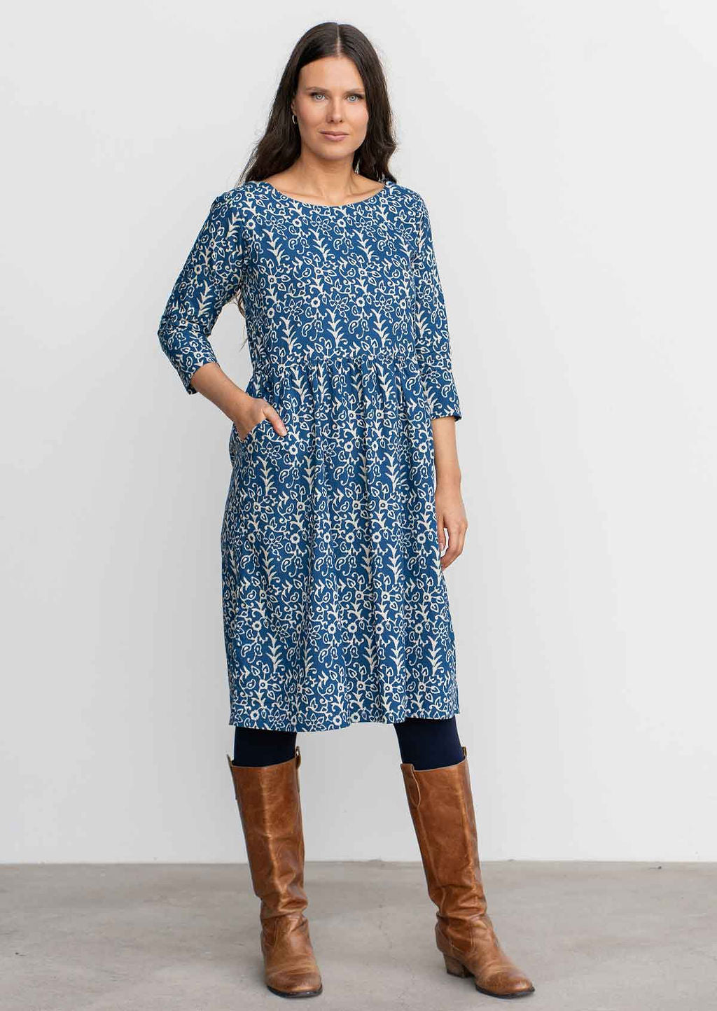 Woman in blue floral knee length sundress with sleeves, 100% cotton with hand in pocket