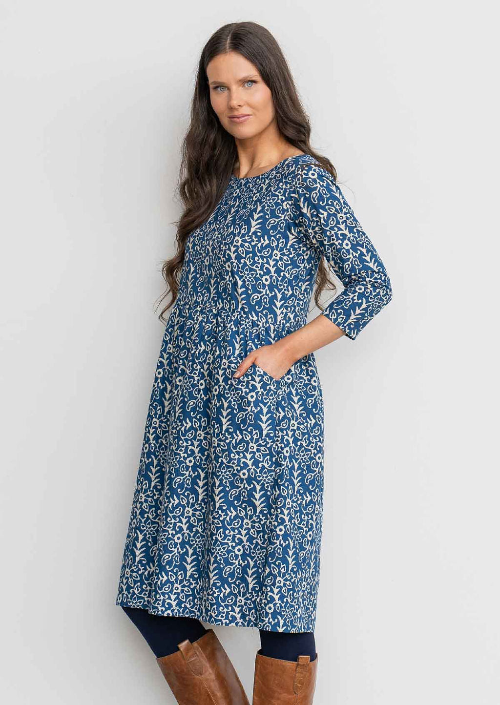 Woman in blue cotton, floral, knee length sundress with sleeves,  with hand in pocket