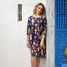 Woman wearing navy blue knee length cotton long sleeve dress with large pink floral print