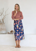 Woman wearing a floral printed navy blue skirt with dusty rose stretch top indoors.