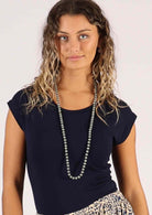 woman wearing long pale grey wooden beads over navy blue t-shirt