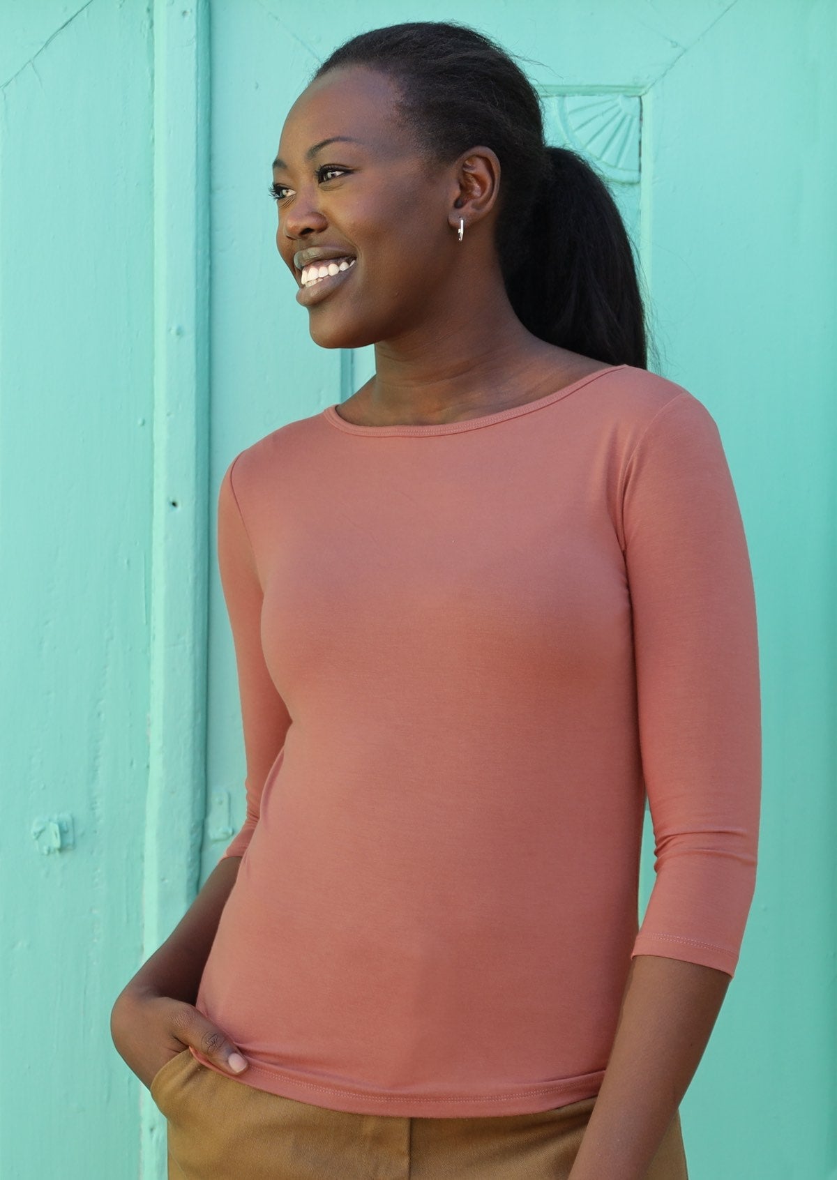 Woman wearing a rayon boat neck dusty pink 3/4 sleeve top.