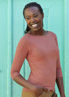 Woman with dark hair wearing a rayon boat neck dusty pink 3/4 sleeve top.