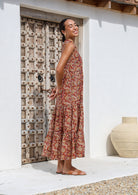 Model standing in sun wearing a sleeves maxi dress with buttoned bodice, tiers and mandarin collar.