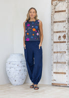 Woman wearing a sleeveless top with colourful polka dots and blue pants and sandals