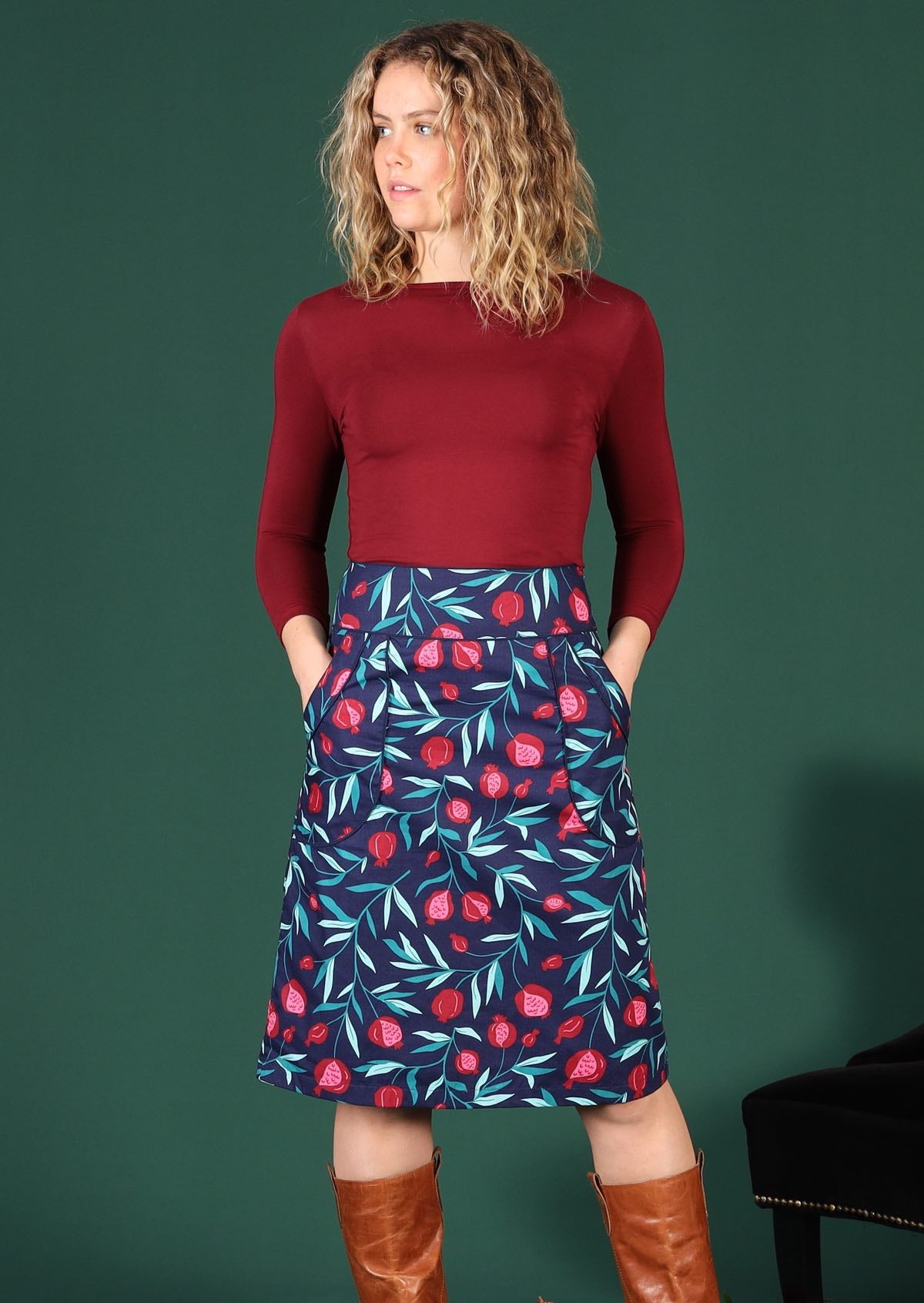Model wears 100% cotton mid length retro skirt in a blue based pomegranate print featuring piped detail pockets 