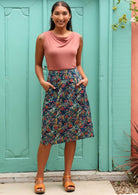 Model wears a high waisted skirt styled with sandals and a sleeveless top. 
